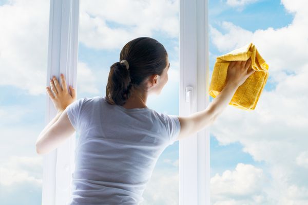 زن جوان در حال شستن پنجره ها