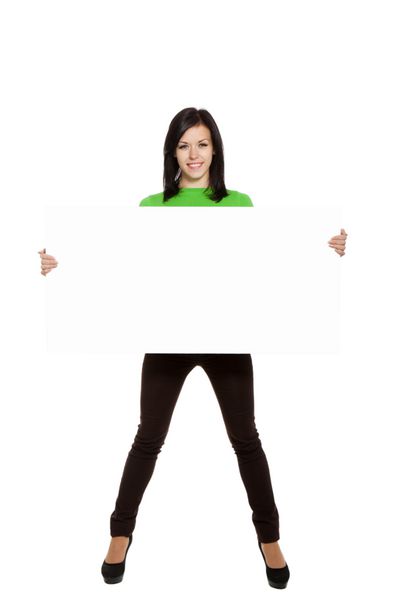 زن جوان لبخند شاد ایستاده تخته خالی نگه دارد دختر جذاب پیراهن سبز می پوشد تمام قد جدا شده روی پس زمینه سفید عکسبرداری استودیویی