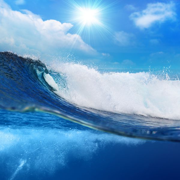 منظره دریا با منظره اقیانوس موج بزرگ اقیانوس موج سواری که توسط خط آبی با آسمان کمی ابری و خورشید تقسیم شده است