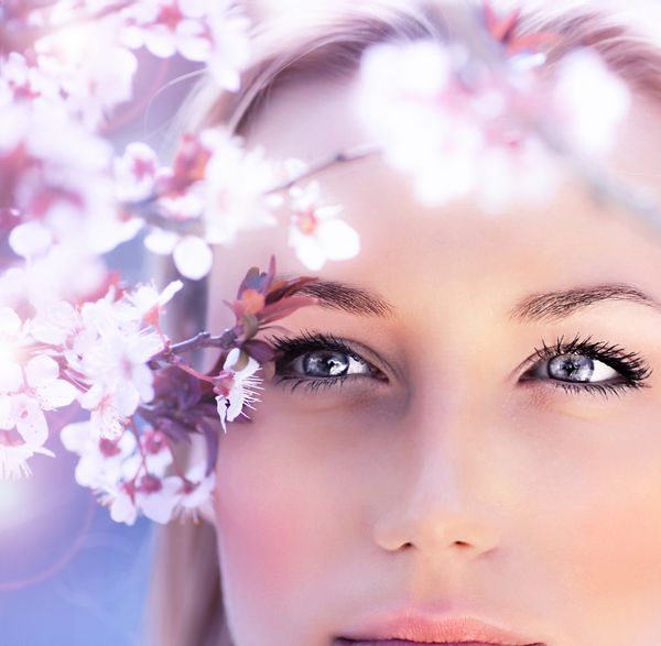 پرتره احساسی یک زن بهاری چهره زیبا از نزدیک روی چشمان آبی زن در حال لذت بردن از شکوفه های گیلاس دختر رویایی با گل های تازه صورتی در فضای باز طبیعت فصلی شاخه درخت و زیبایی طبیعی