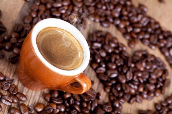 فنجان قهوه و شکل قلب ساخته شده از دانه های برشته شده