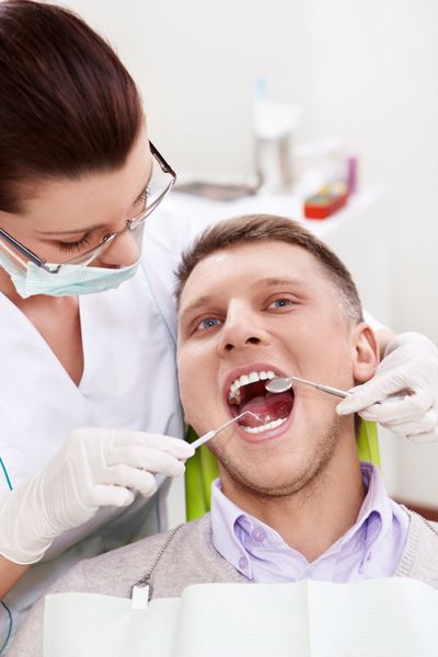 دندانپزشک دندان های بیمار را درمان می کند