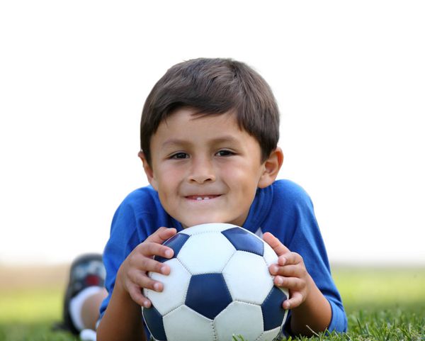 پسر جوان اسپانیایی تبار با توپ فوتبال با جداسازی جزئی در پس‌زمینه سفید