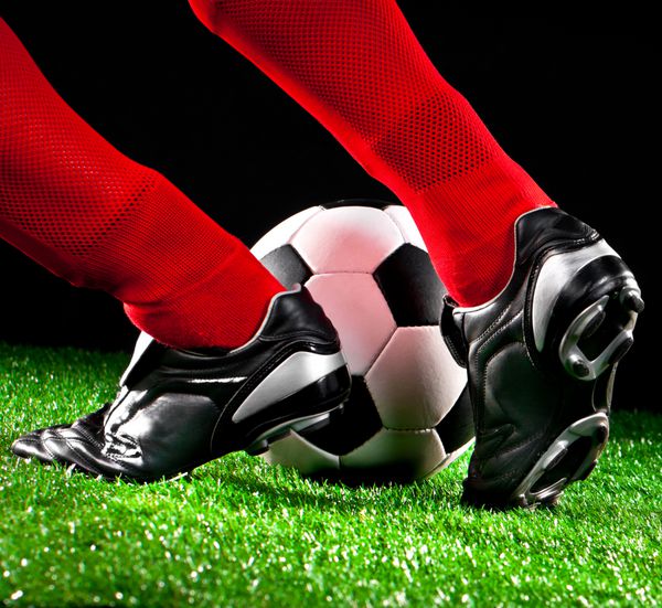 توپ و پاهای فوتبال در زمین فوتبال