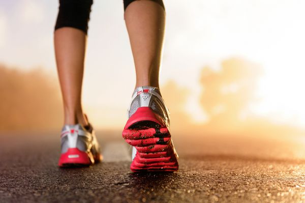 پاهای دونده در حال دویدن در نزدیکی جاده روی کفش تناسب اندام زن طلوع آفتاب دویدن تمرین دویدن مفهوم سلامتی