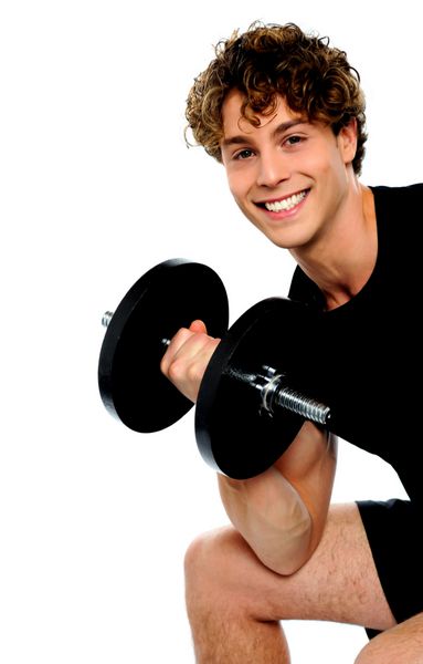 مرد جوان قوی که با دمبل ورزش می کند در استودیو در پس زمینه سفید عکس گرفته شده است