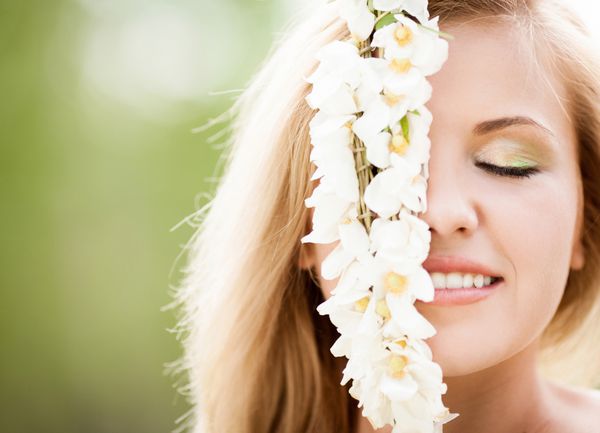 زن جوان بلوند زیبا با گلهای سفید در فضای باز