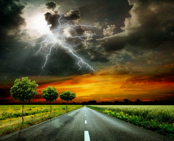 جاده از میان چمنزار و آسمان طوفانی