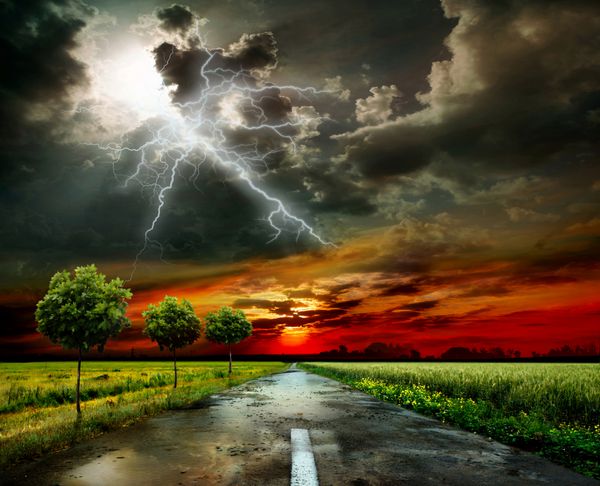 جاده از میان چمنزار و آسمان طوفانی