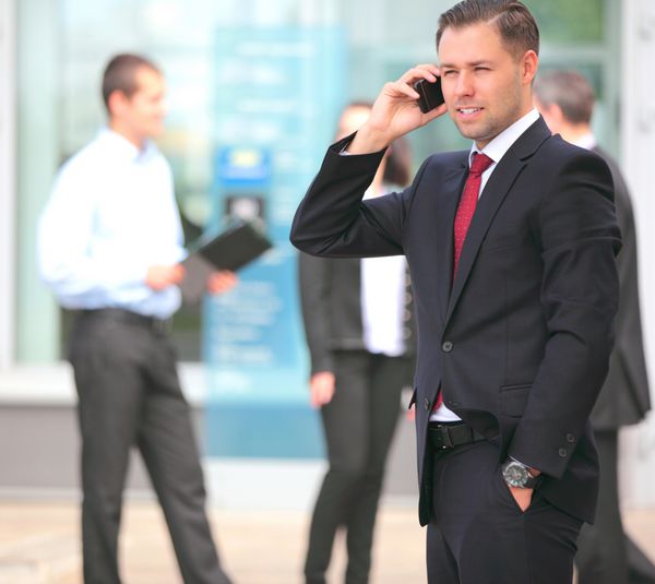 یک مرد جوان خوش تیپ تاجر با تلفن در ساختمان اداری