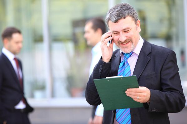 یک مرد تاجر خوش تیپ با تلفن در ساختمان اداری