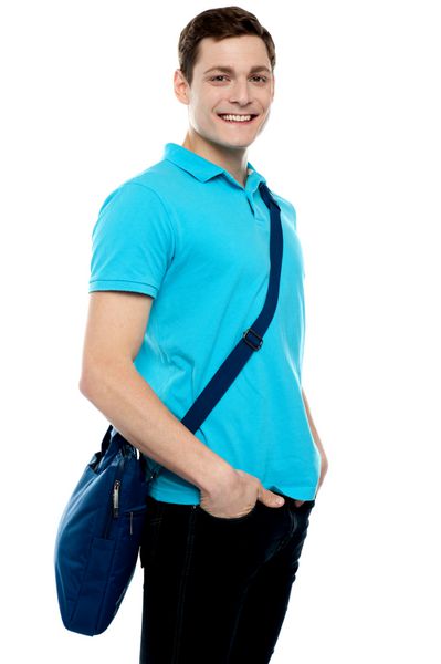 پسر نوجوانی که کیف لپ‌تاپ را روی شانه‌ها حمل می‌کند و دست‌ها در جیب است