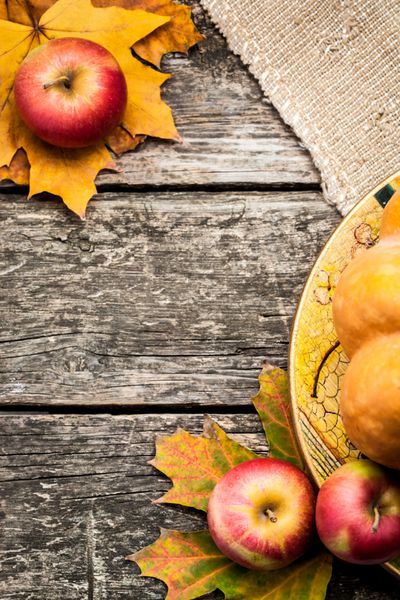 قاب پاییزی از سیب و برگ های افرا روی میز چوبی قدیمی مفهوم روز شکرگزاری