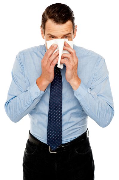 مرد جوانی که سرما خورده است عطسه کردن و تمیز کردن بینی با دستمال کاغذی