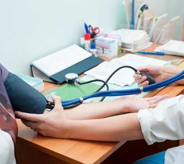 یک پزشک فشار خون بیمار را می گیرد