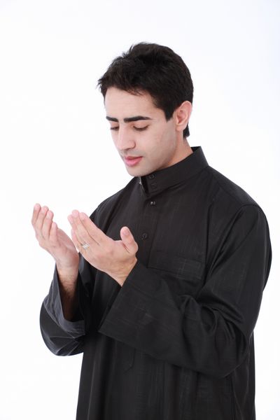 مرد جوان مسلمان با پوشیدن لباس سنتی در حال عبادت و اجرای ایمان اسلامی بر روی یک پس‌زمینه سفید جدا شده و بدون درز