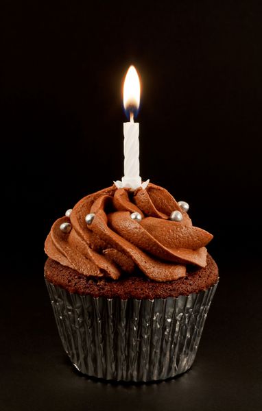 یک کیک فنجانی شکلاتی خانگی با یک شمع روشن برای جشن تولد یا سالگرد دیگر