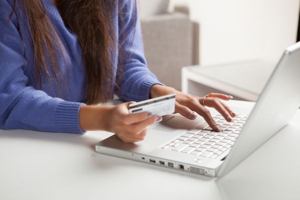 دختر جوان اسپانیایی تبار از رایانه برای خرید آنلاین کارت اعتباری استفاده می کند