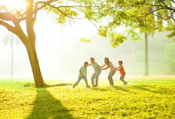خانواده آسیایی خوشحال در حال بازی با هم در پارک در فضای باز