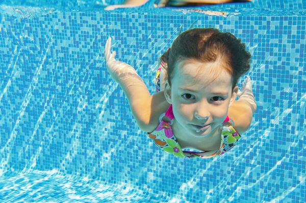 کودک زیر آب خندان شاد در استخر شنا دختر زیبای شنا و سرگرمی ورزش کودکان در تعطیلات تابستانی خانوادگی تعطیلات سالم فعال