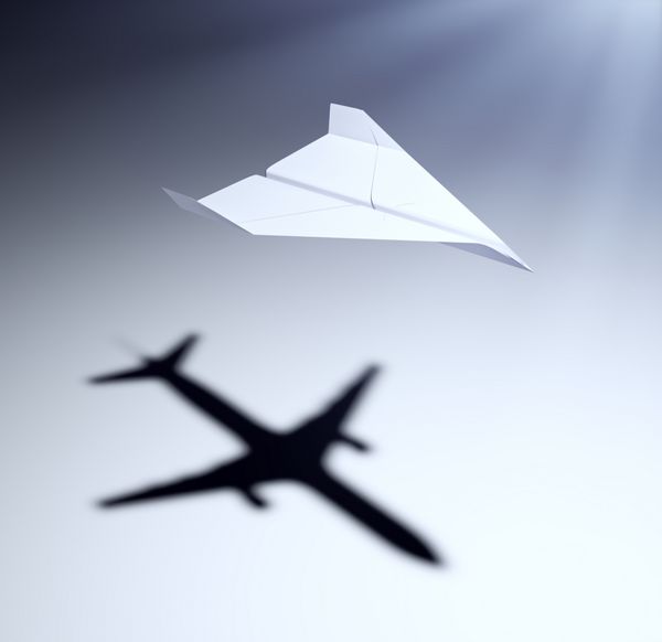 هواپیمای کاغذی که سایه ای از هواپیمای جت می اندازد - تصویر مفهومی بینش و آرزوها