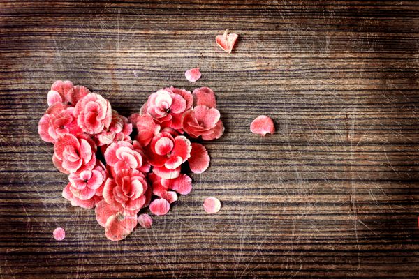 قلب قدیمی از گل های روی میز چوبی