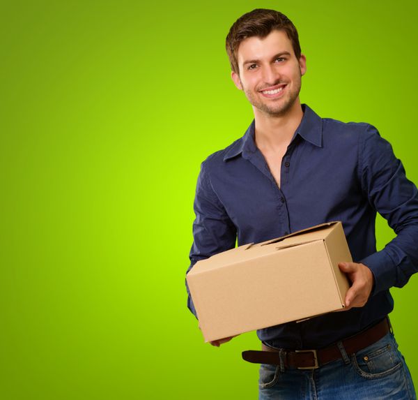 مرد جوانی که جعبه مقوایی در پس زمینه سبز در دست دارد