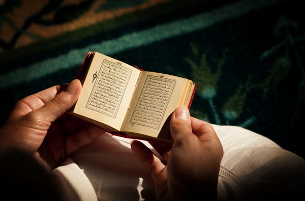 زن جوان در حال خواندن قرآن در مسجد