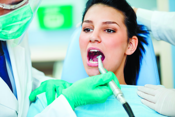 بیمار زن با دهان باز در حین درمان مته در دندانپزشک