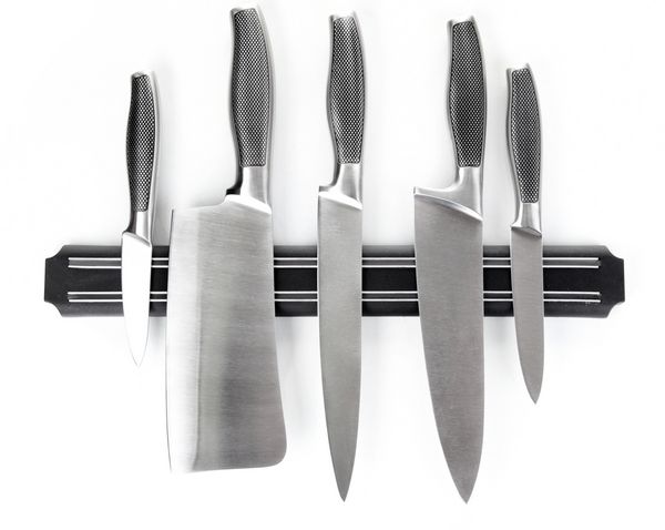 مجموعه ای از چاقوها روی نگهدارنده مغناطیسی جدا شده روی سفید