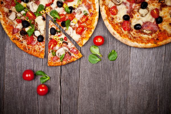 پیتزاهای خوشمزه ایتالیایی که روی میز چوبی سرو می شوند
