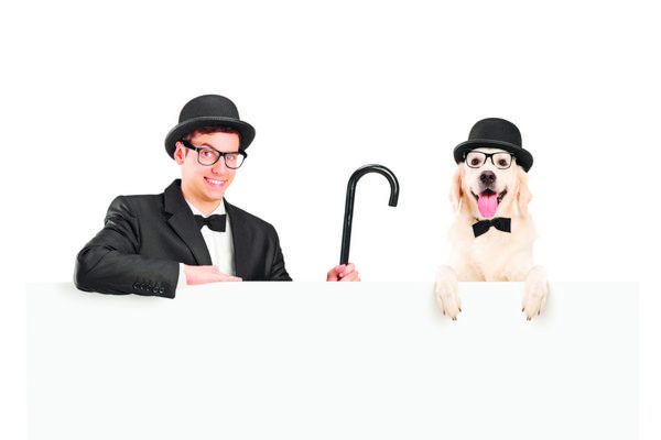 مجری با کت و شلوار کلاه یکپارچهسازی با عصا و با سگی که پشت تابلویی جدا شده روی سفید ژست گرفته است