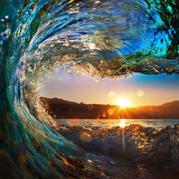 موج رنگارنگ اقیانوسی که در زمان غروب آفتاب فرو می ریزد