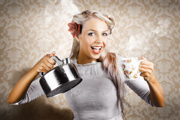 زن زیبای جوان در حال نوشیدن یک فنجان قهوه گرم در پس زمینه قهوه ای قدیمی