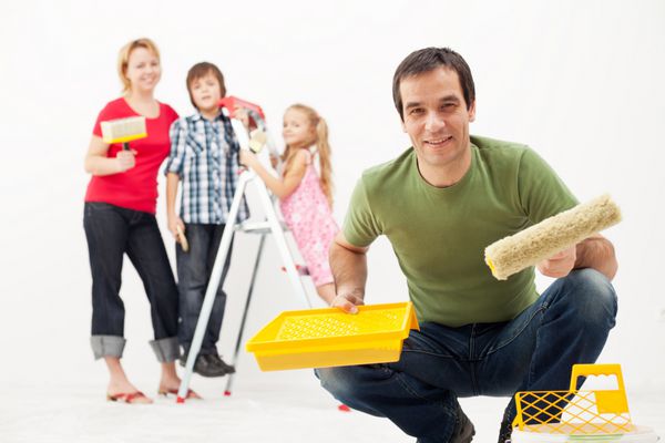 خانواده شاد با بچه هایی که خانه خود را دوباره تزئین می کنند - با هم نقاشی می کنند