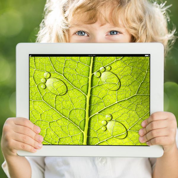 کودک شاد که تبلت رایانه شخصی را با عکس بافت برگ سبز در فضای باز در بهار در دست دارد مفهوم اکولوژی