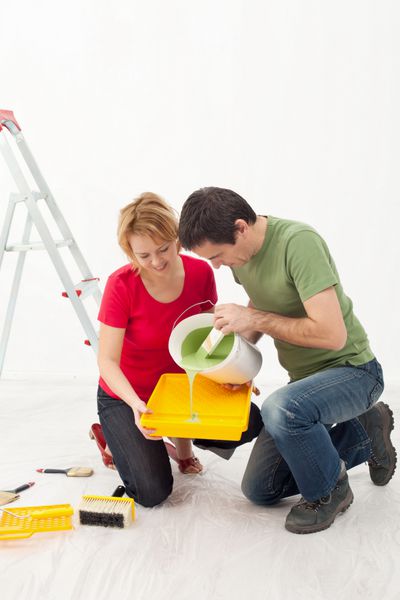 زن و شوهر جوان در حال نقاشی خانه خود - ریختن رنگ