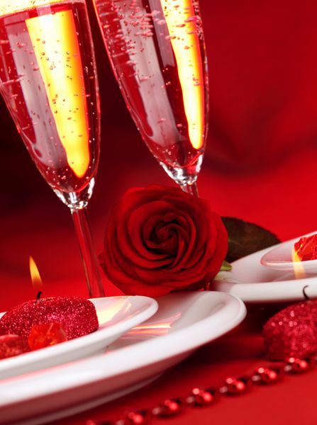 تصویری از طبیعت زیبای شام روز ولنتاین دو لیوان شامپاین نوشیدنی الکلی نوشیدنی عاشقانه شراب گازدار رز قرمز و شمع چیدمان میز جشن مفهوم عشق