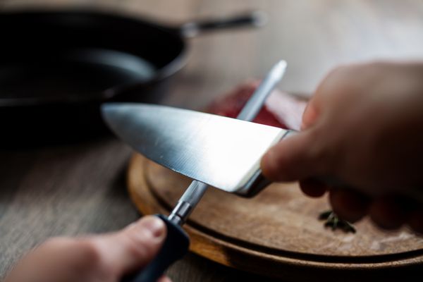 مردی در حال تیز کردن چاقو برای بریدن استیک گوشت گاو