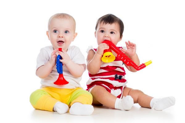 دختر بچه های خنده دار با اسباب بازی های موزیکال جدا شده در زمینه سفید