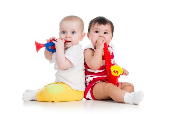 دختر بچه های خنده دار با اسباب بازی های موزیکال جدا شده در زمینه سفید