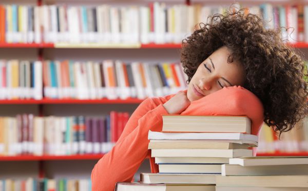 دانش آموزی که روی میز در کتابخانه می خوابد