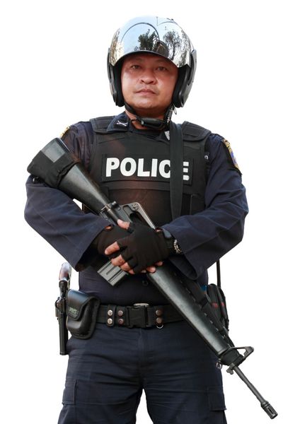 افسر پلیس تفنگ را در پس زمینه سفید در دست دارد
