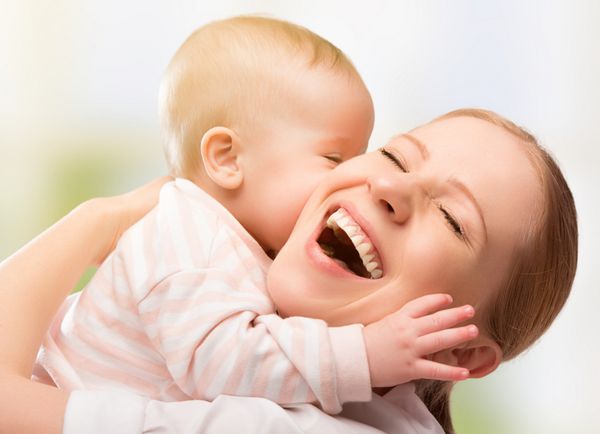 خانواده شاد مادر و نوزاد در حال بوسیدن خندیدن و در آغوش گرفتن