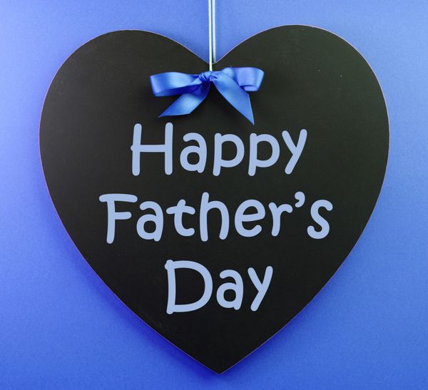 پیام تبریک روز پدر که روی یک تخته سیاه با روبان آبی در پس زمینه آبی نوشته شده است