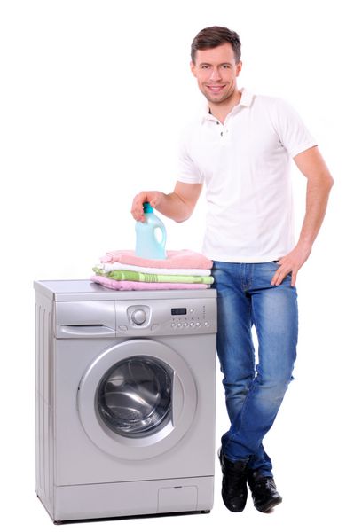 مرد جوان در کنار ماشین لباسشویی ایزوله شده در پس زمینه سفید