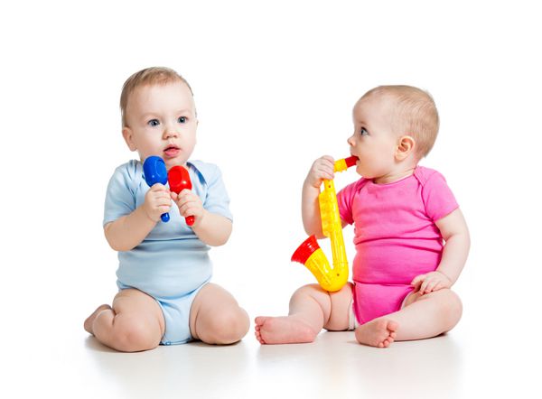 نوزادان دختر و پسر اسباب بازی های موزیکال بازی می کنند جدا شده در زمینه سفید