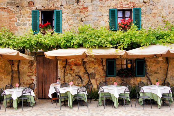 میز و صندلی های کافه بیرون ساختمان سنگی عجیب و غریب در توسکانی ایتالیا