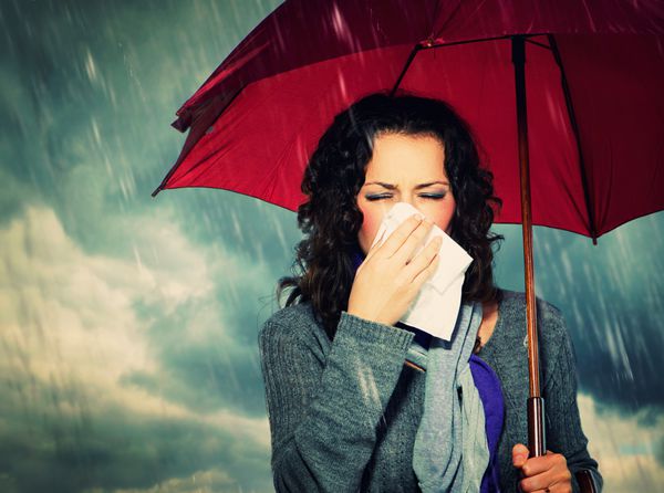 عطسه زن با چتر بر روی پس زمینه باران پاییزی زن بیمار در فضای باز آنفولانزا دختر سرما خورد عطسه کردن در بافت سردرد ویروس هوای بد