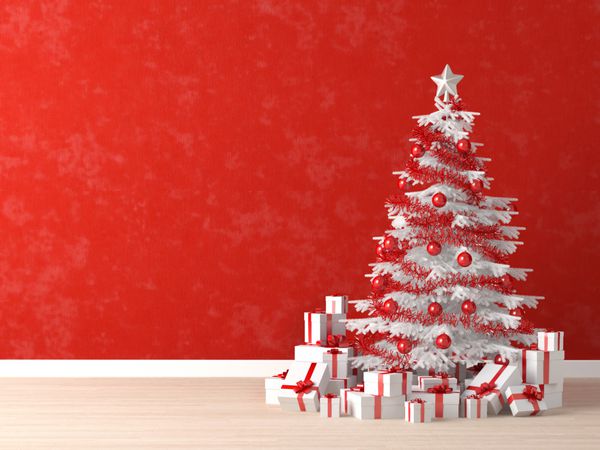 درخت کریسمس سفید و قرمز تزئین شده با هدایای زیادی روی یک دیوار قرمز پر جنب و جوش برای پس زمینه فضای کپی در سمت چپ